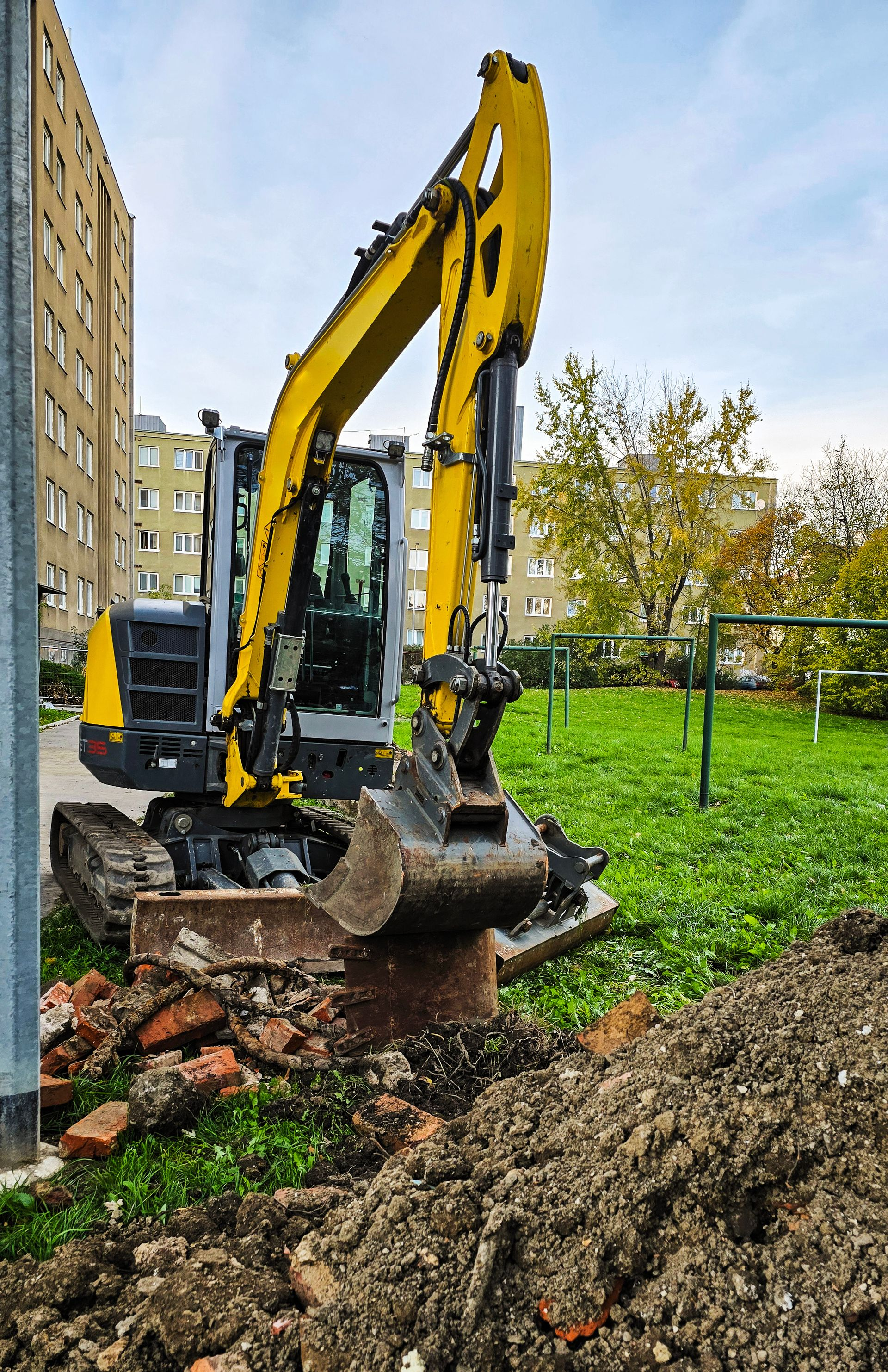 Une minipelle ayant son godet levé à côté d'un tas de terre