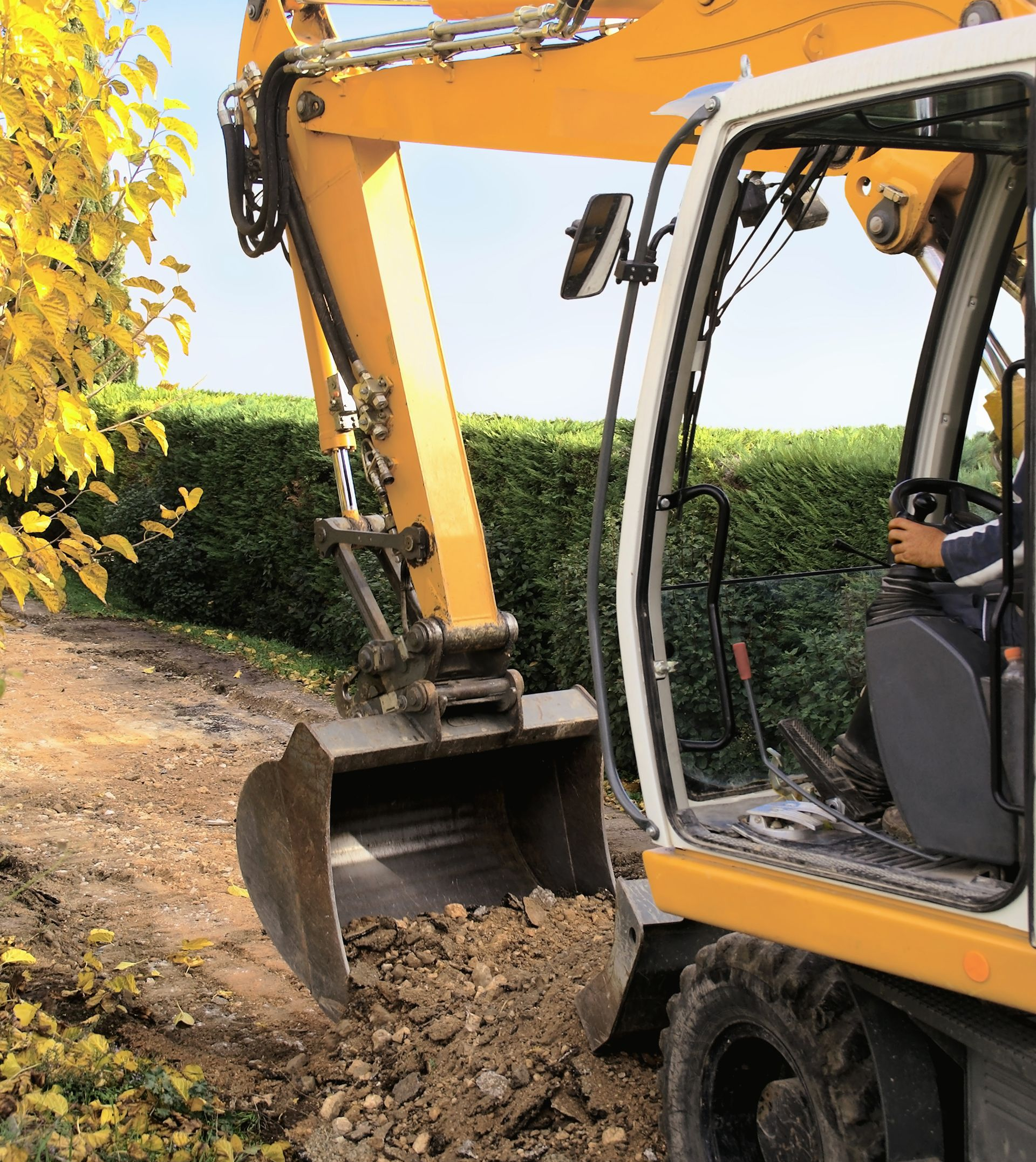 Une tractopelle ramassant de la terre à côté d'une haie