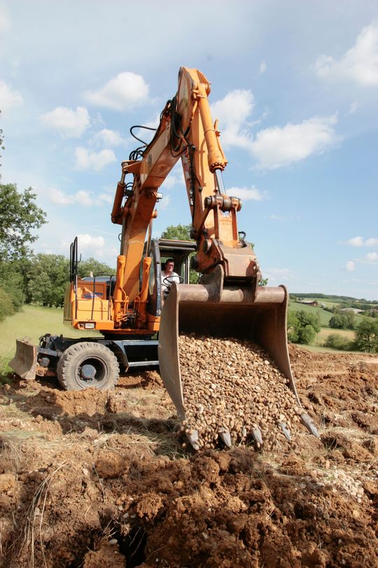Une tractopelle ayant dans sa pelle des graviers