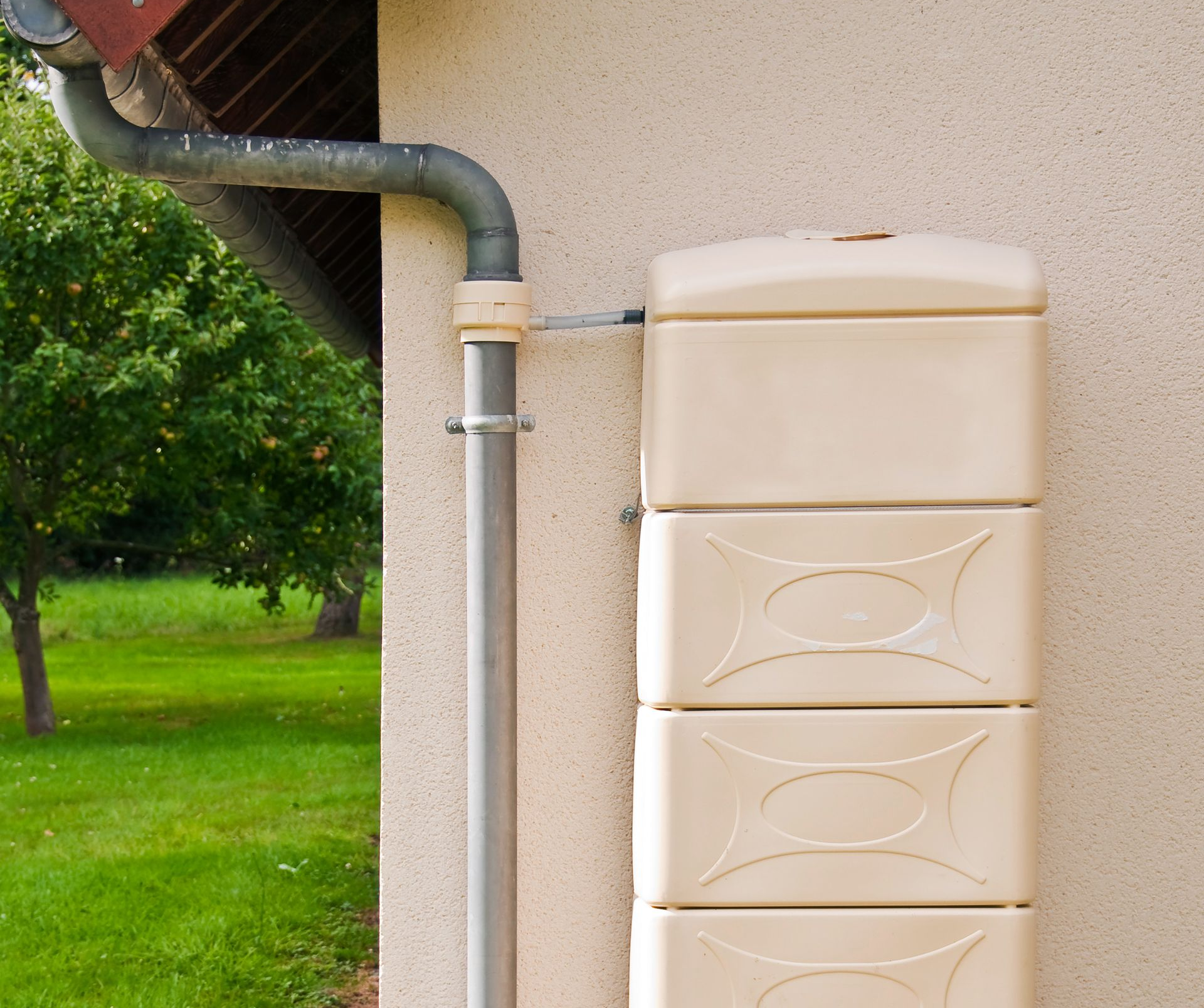 Un réservoir avec un robinet devant un mur raccordé à la gouttière