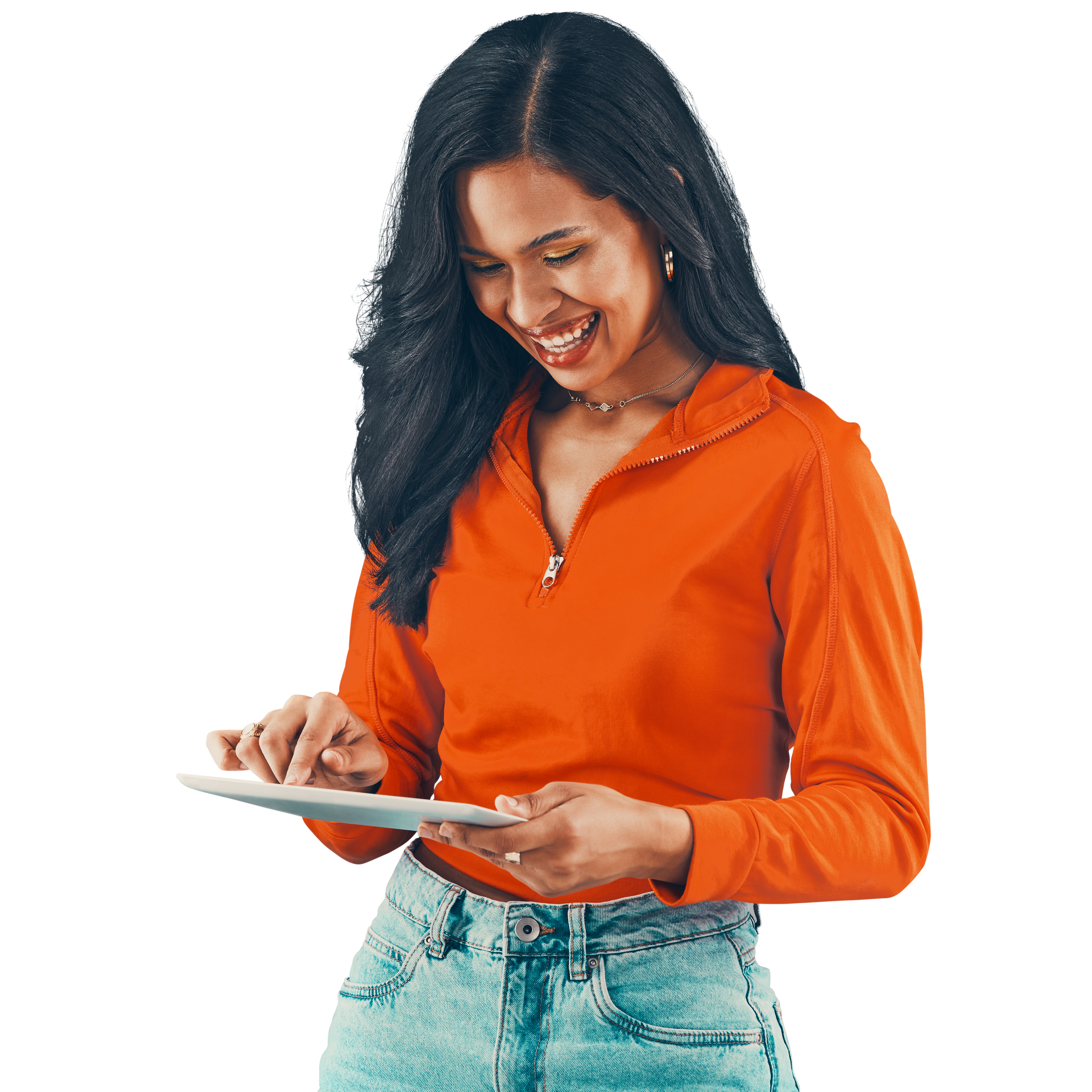 Femme aux cheveux foncés, souriante, regardant une tablette, vêtue d'une chemise orange et d'un jean.