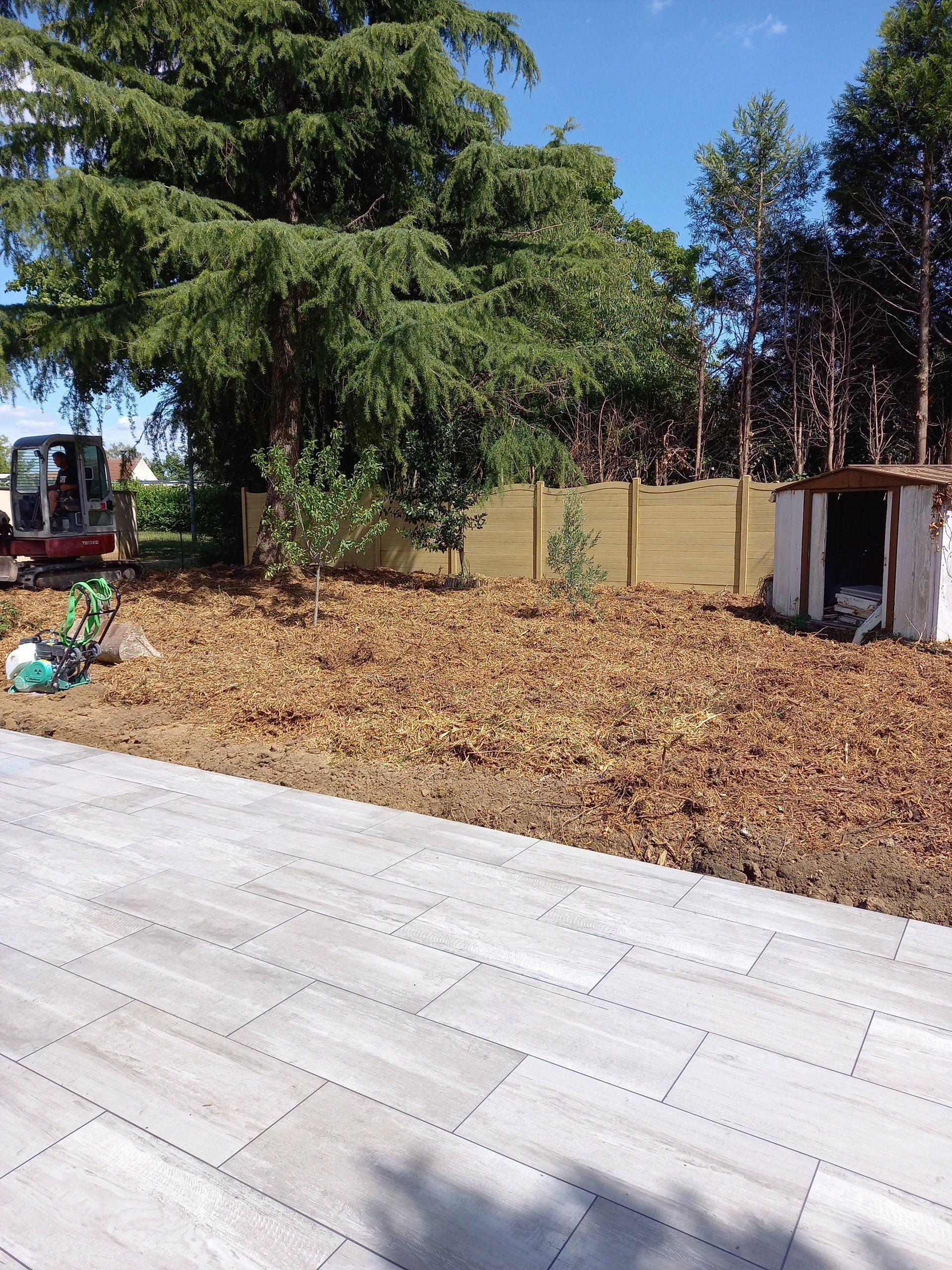 Terrasse avec carrelage gris et terrain avec clôture imitation bois