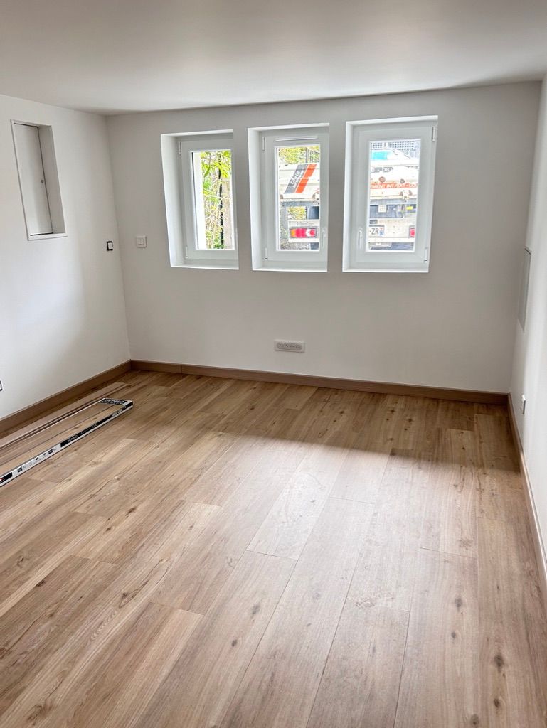 Pièce vide avec parquet, murs blancs et fenêtres PVC