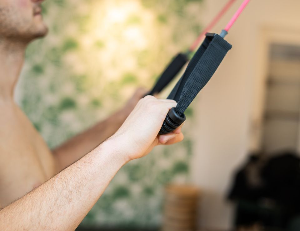 Ein Mann ohne Hemd hält ein Widerstandsband in seinen Händen.