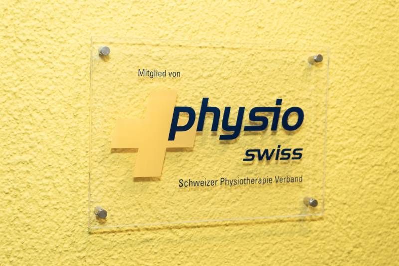 Eine gelbe Wand mit einem Schild mit der Aufschrift „Physio Swiss“. Foto von der Physiotherapie Kriens
