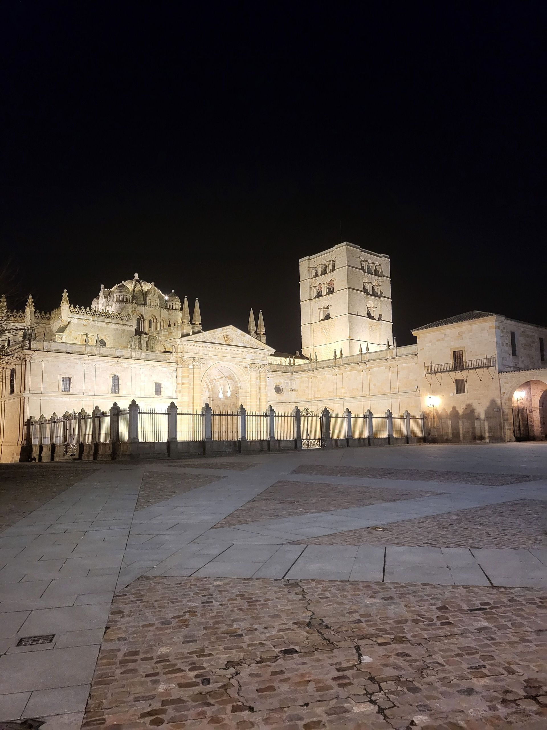 Un gran edificio con una torre al fondo está iluminado por la noche.