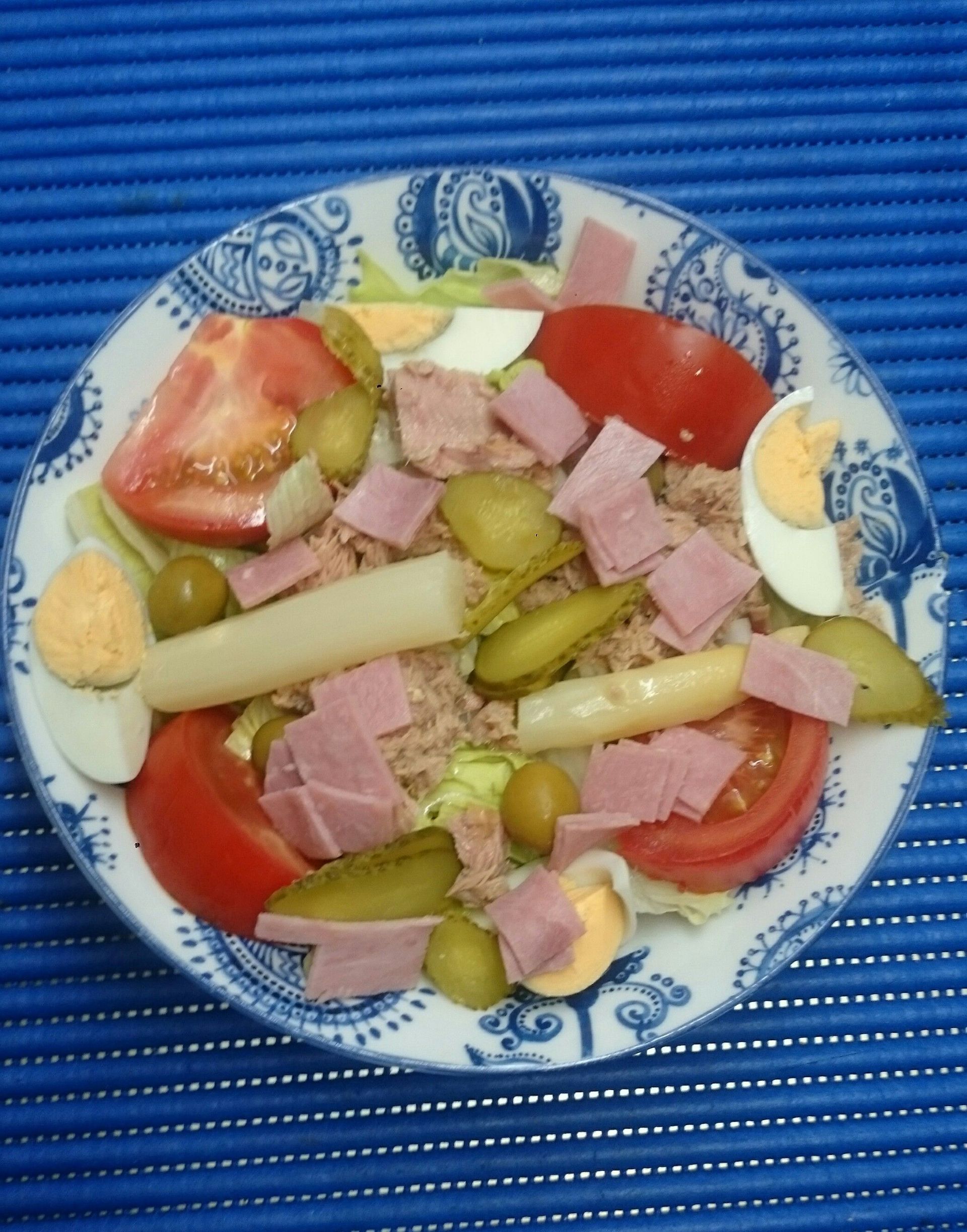 Un plato azul y blanco con una ensalada encima.
