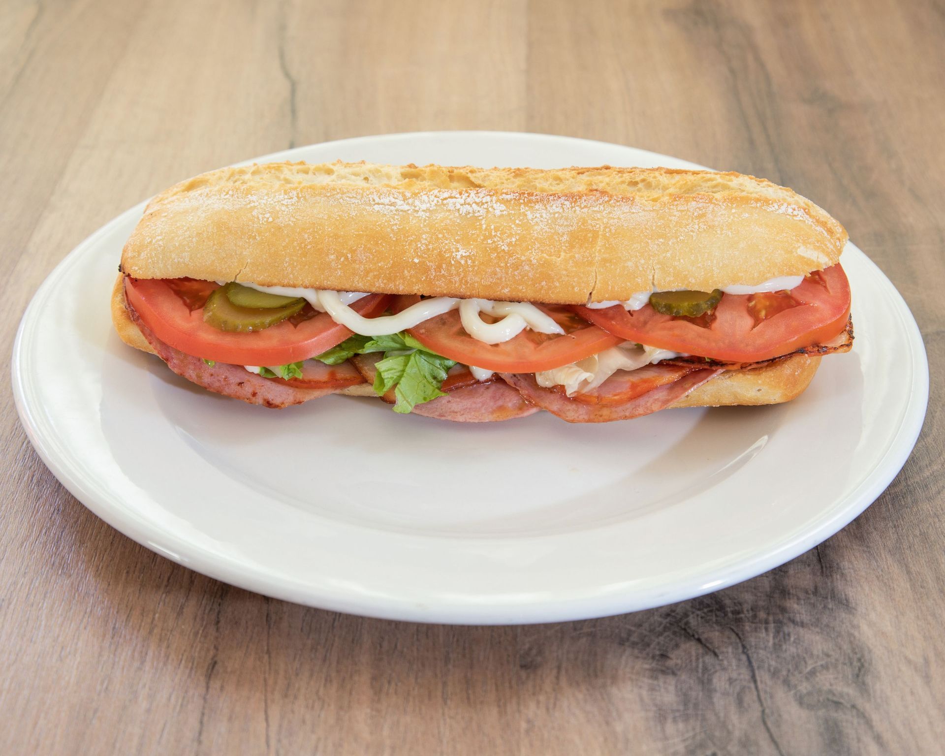 Un sándwich en un plato blanco sobre una mesa de madera.