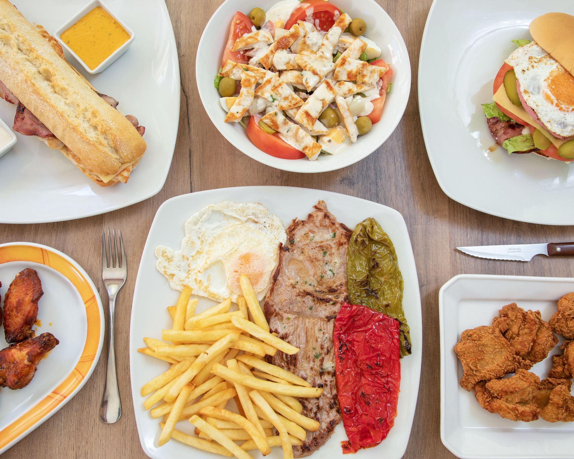 Una mesa cubierta de platos de comida que incluían patatas fritas y un sándwich.