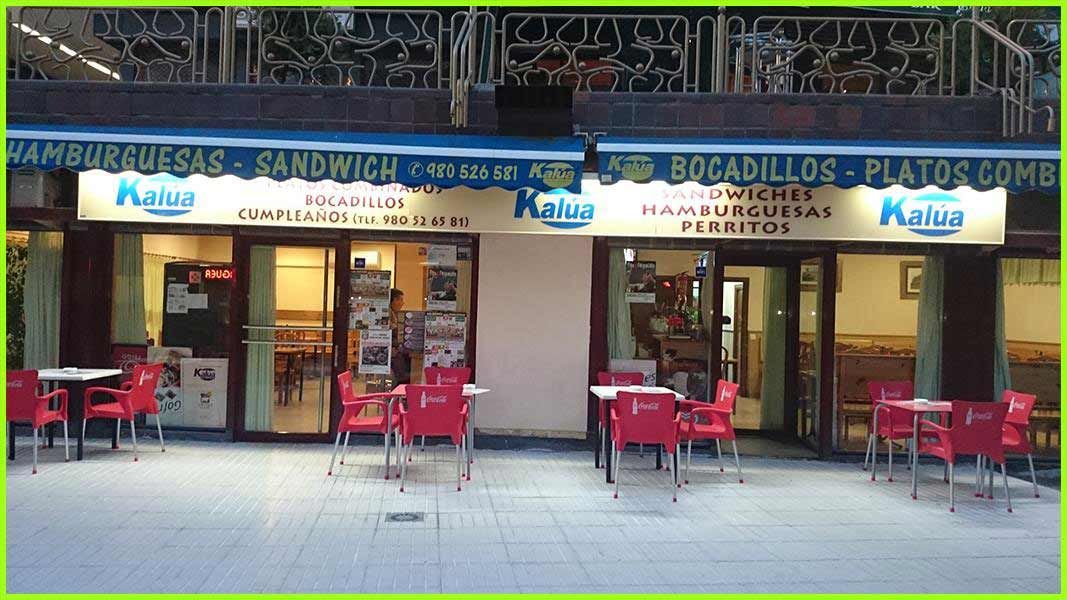Un restaurante llamado hamburguesas sandwich tiene mesas y sillas afuera