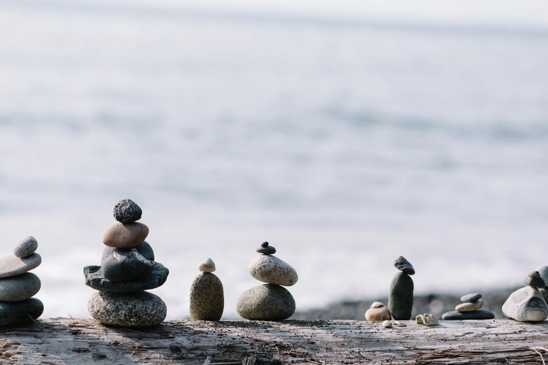 Piedras apiladas a lo largo de una playa con el océano desenfocado de fondo.