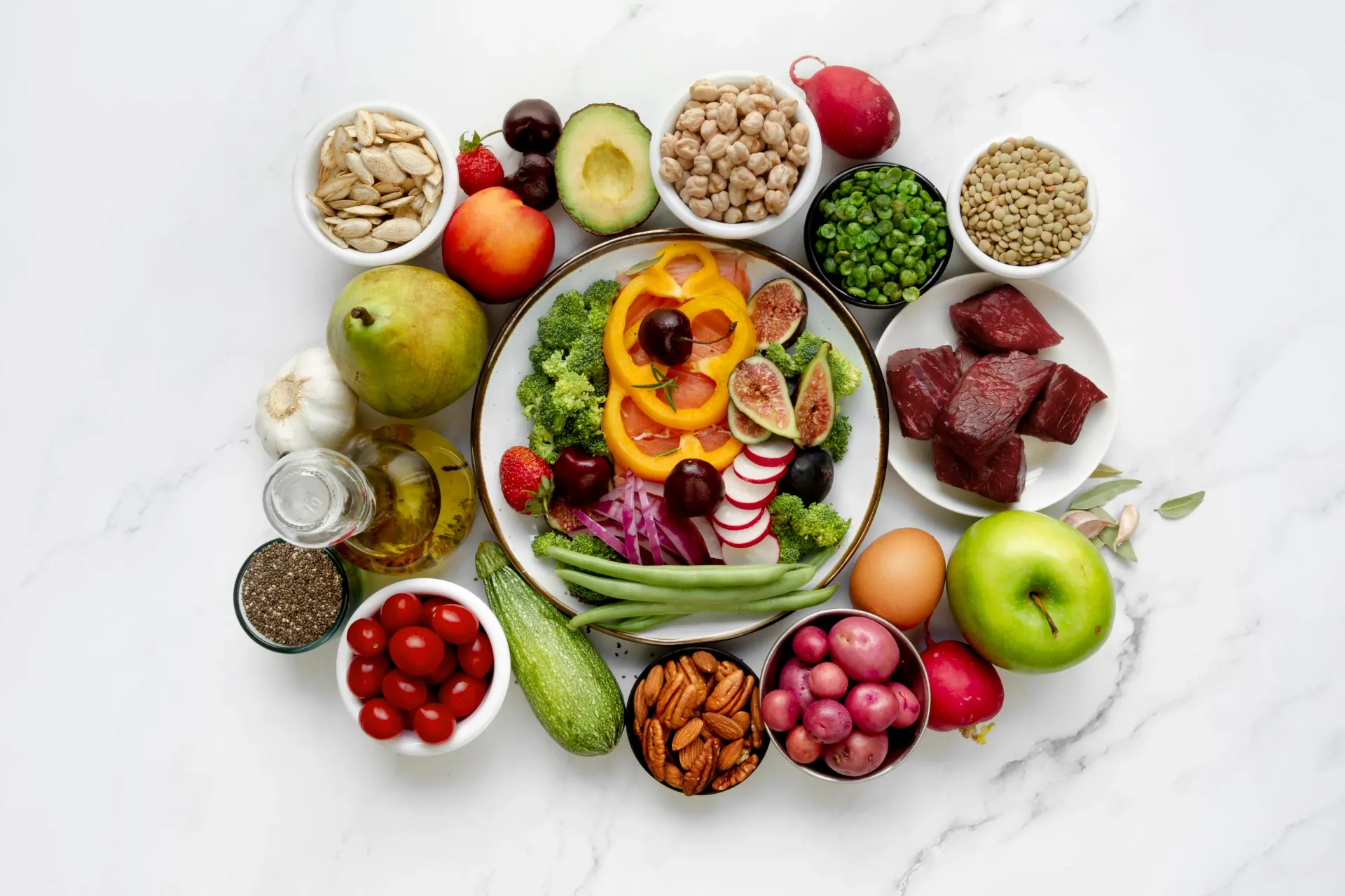 Surtido colorido de frutas, verduras, cereales, frutos secos y semillas dispuestos en un expositor circular de alimentos saludables.