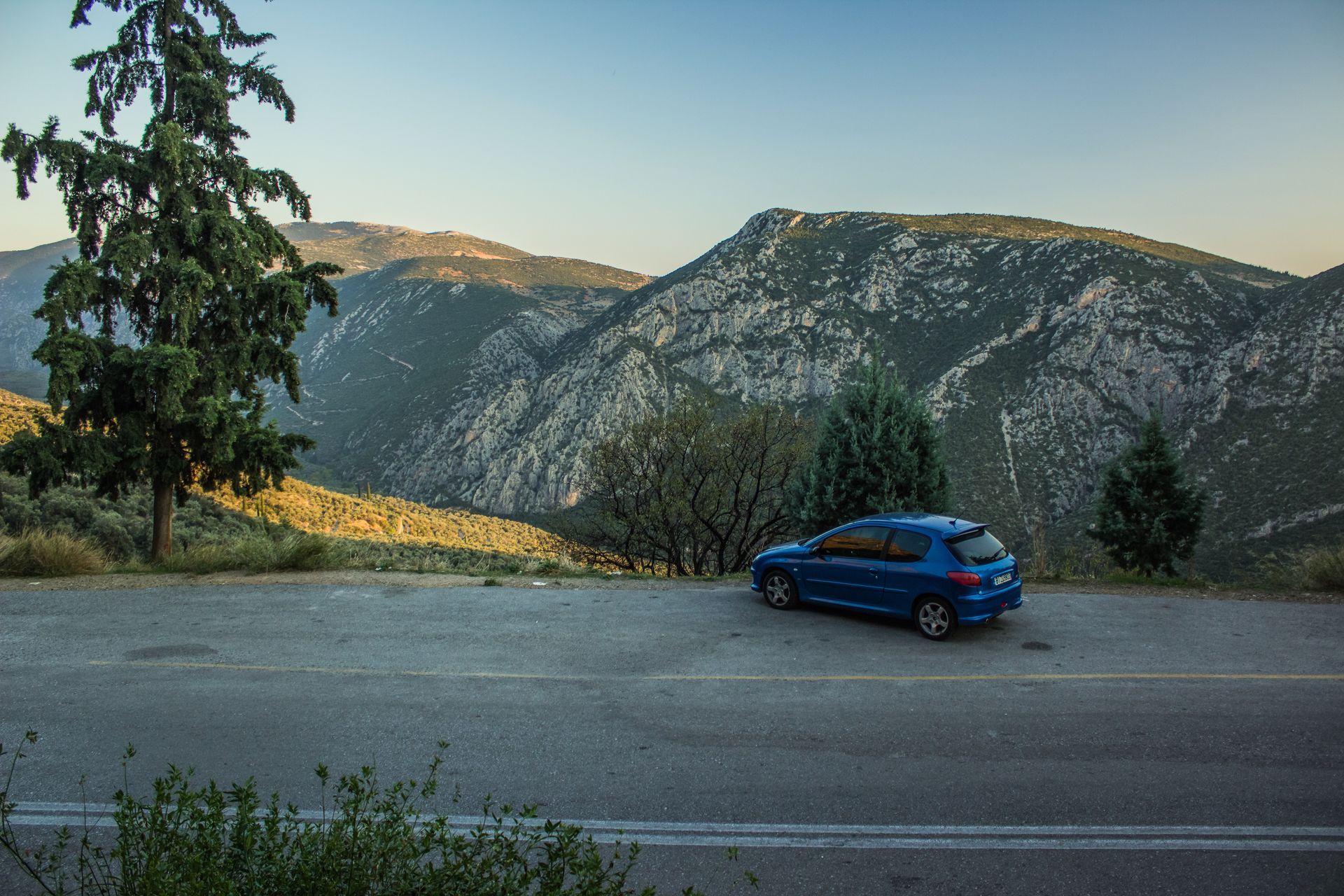 Paysage montagneux avec une Peugeot bleue en bord de route