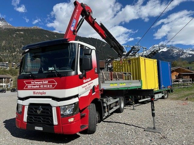 Ein rot-weisser Mietsäppler-Lkw mit Kran steht im Freien.