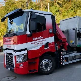 Ein rot-weisser Mietsäppler-Lkw mit Kran steht im Freien.