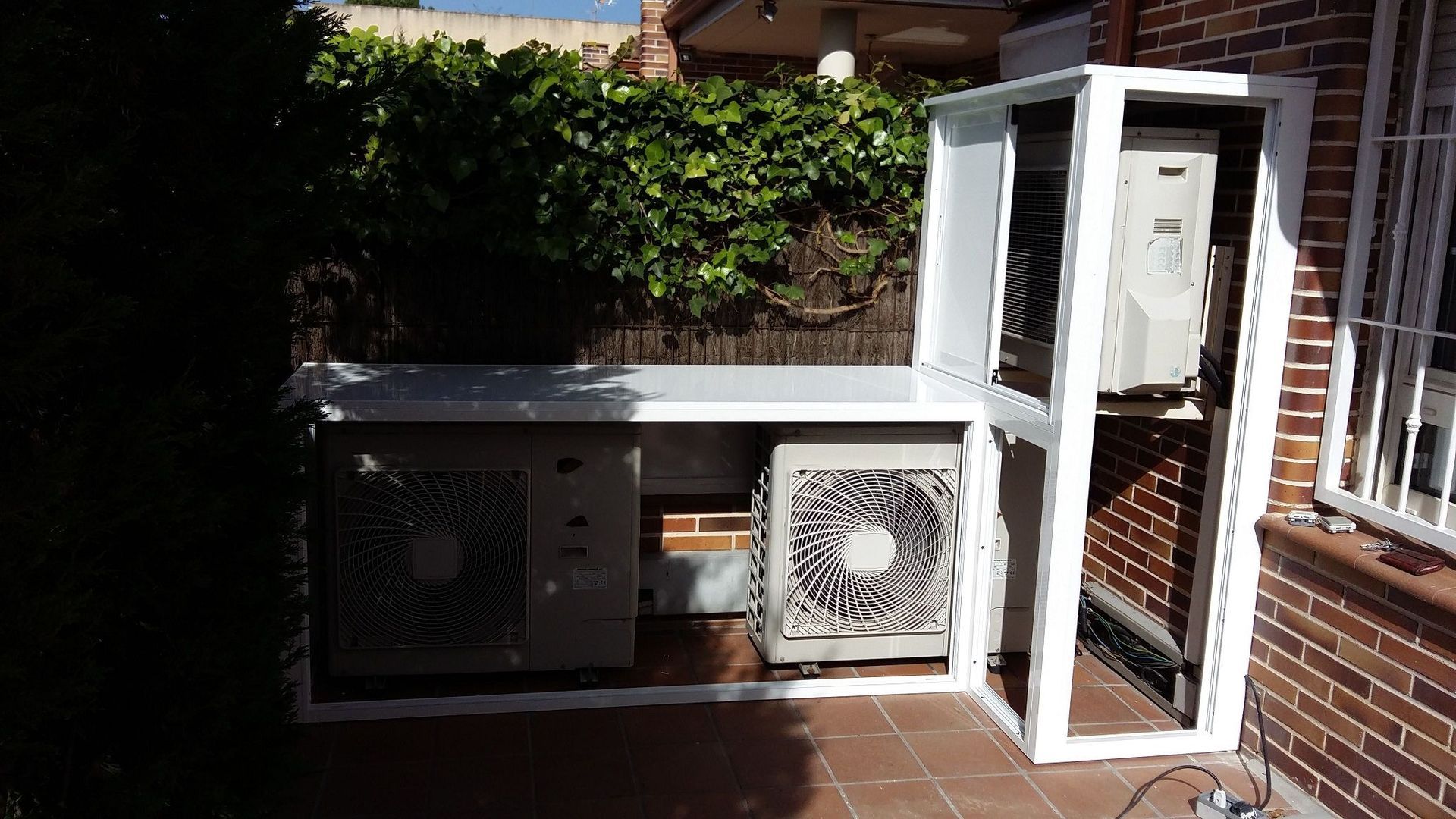 Dos aparatos de aire acondicionado están situados fuera de un edificio de ladrillos.