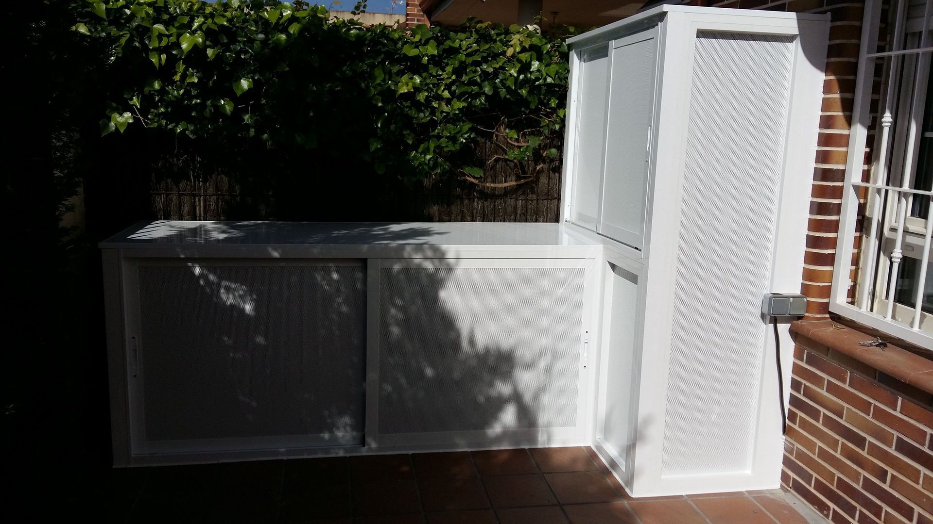 Un armario blanco está sentado en el costado de un edificio de ladrillos.