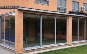 Un edificio de ladrillo con muchas ventanas y puertas corredizas de vidrio.