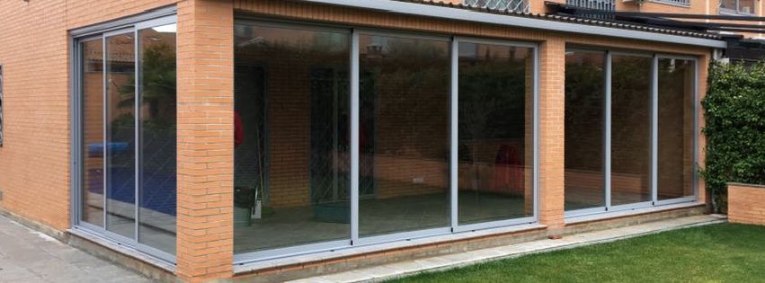 Una casa de ladrillo con un gran porche de vidrio con puertas corredizas de vidrio.