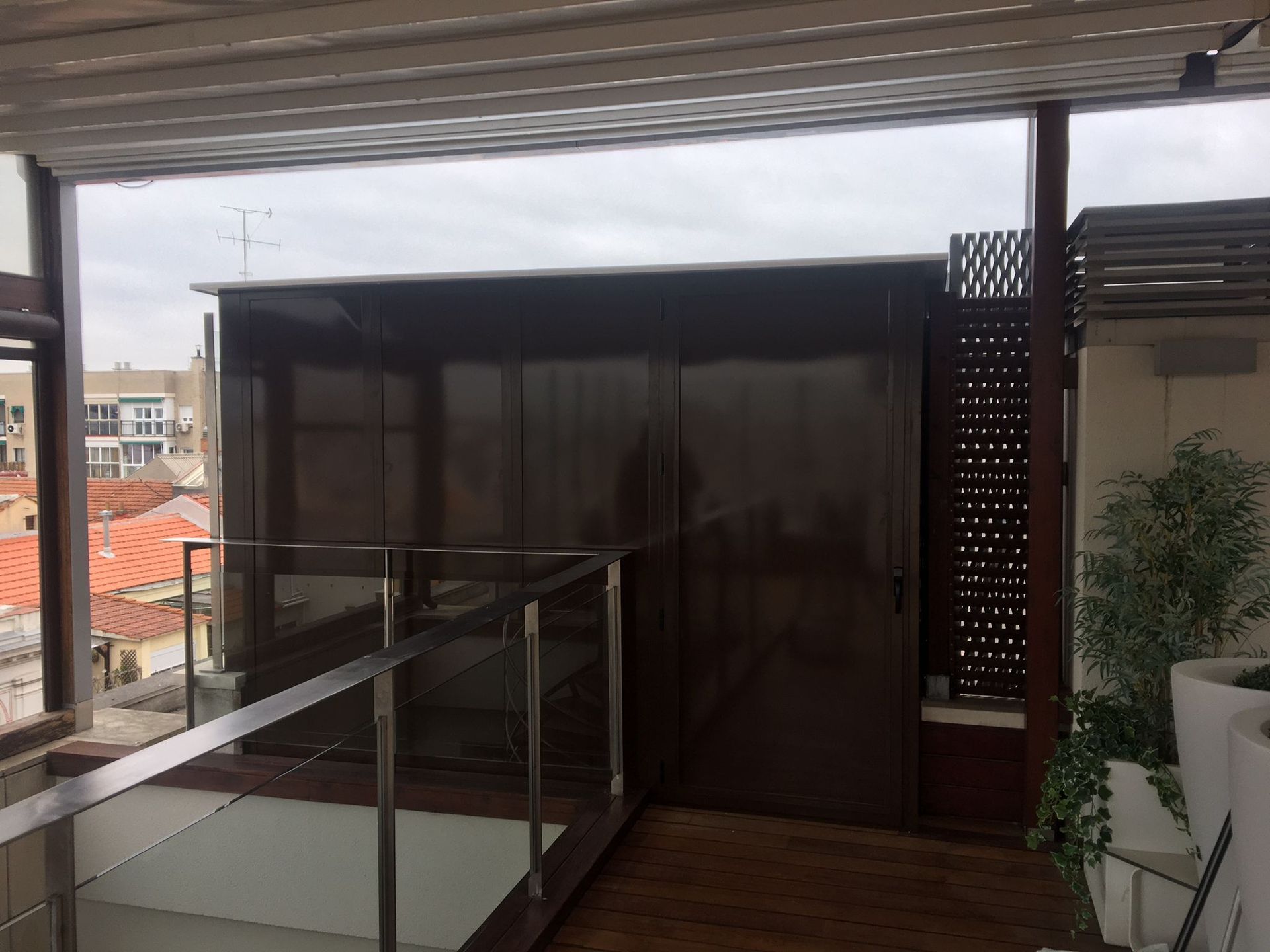 Un balcón con barandilla de acero inoxidable y puerta corrediza de vidrio.