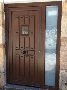 Una puerta de madera con una ventana de vidrio está en una pared de piedra.
