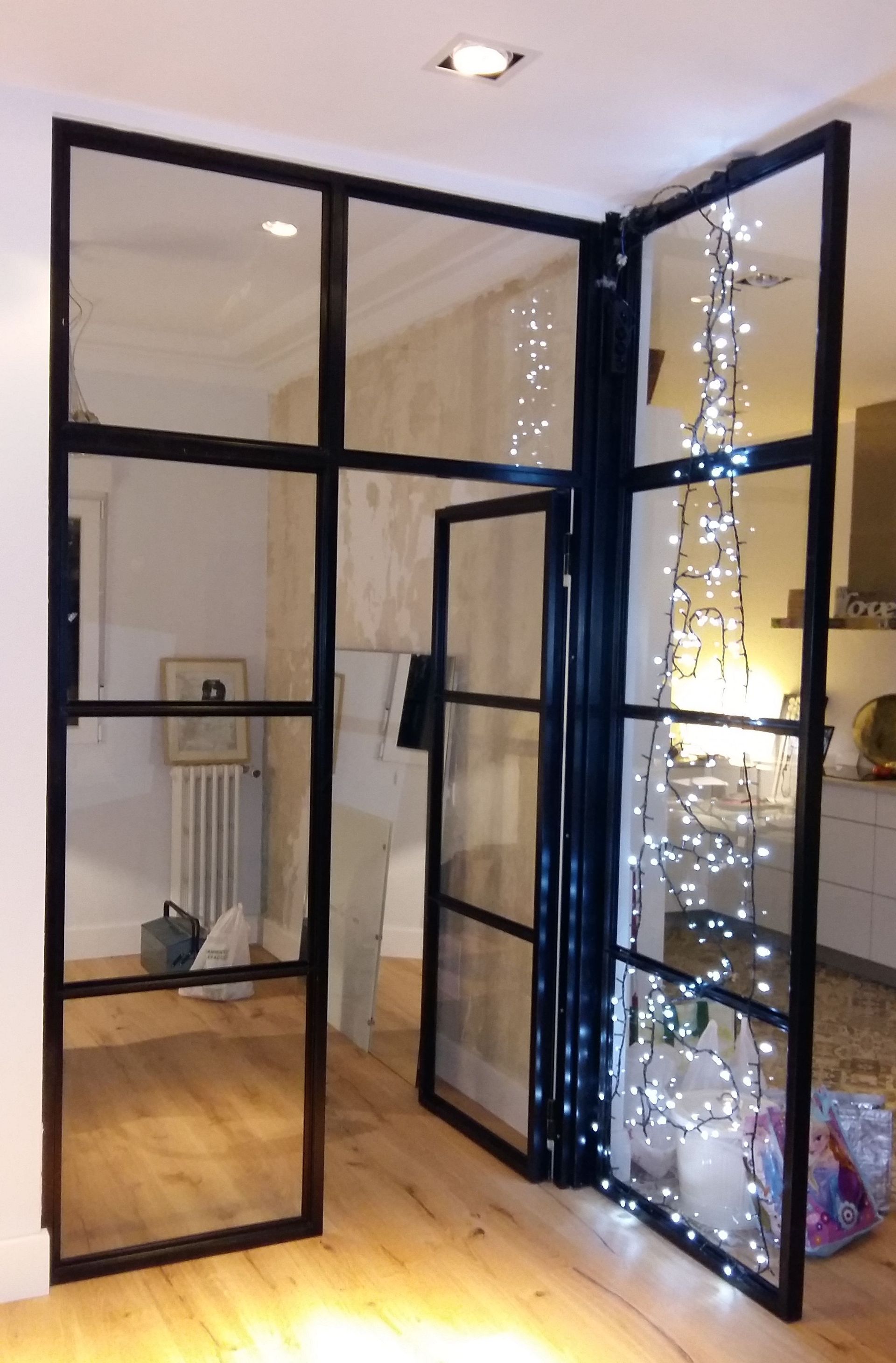 Una habitación con un árbol de Navidad detrás de una puerta de cristal.