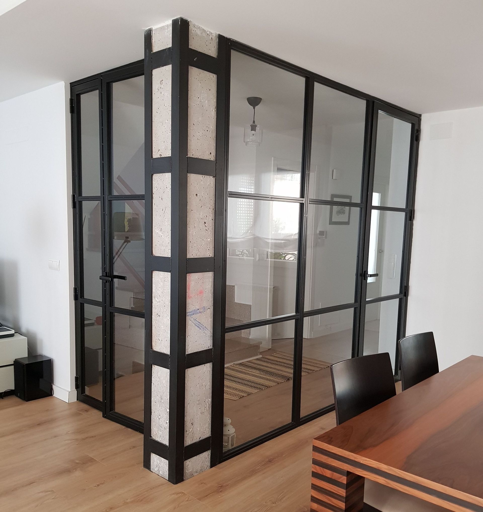 Una habitación con una mesa y sillas y una pared de cristal.