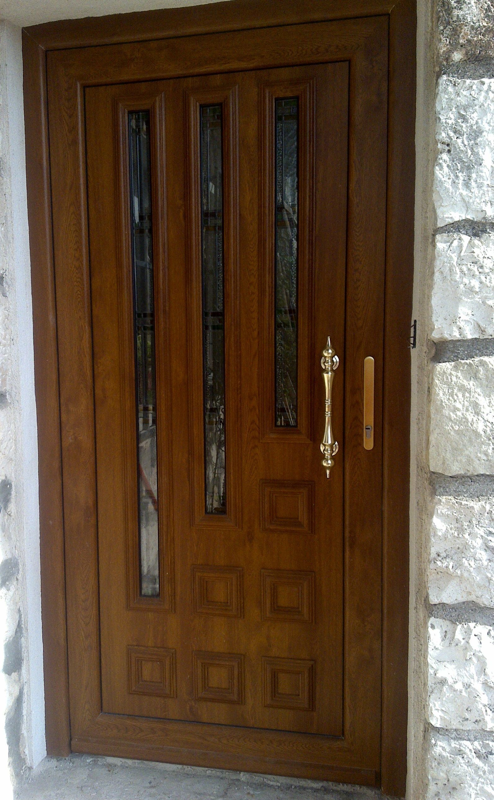 Una puerta de madera con tirador dorado está en una pared de piedra.