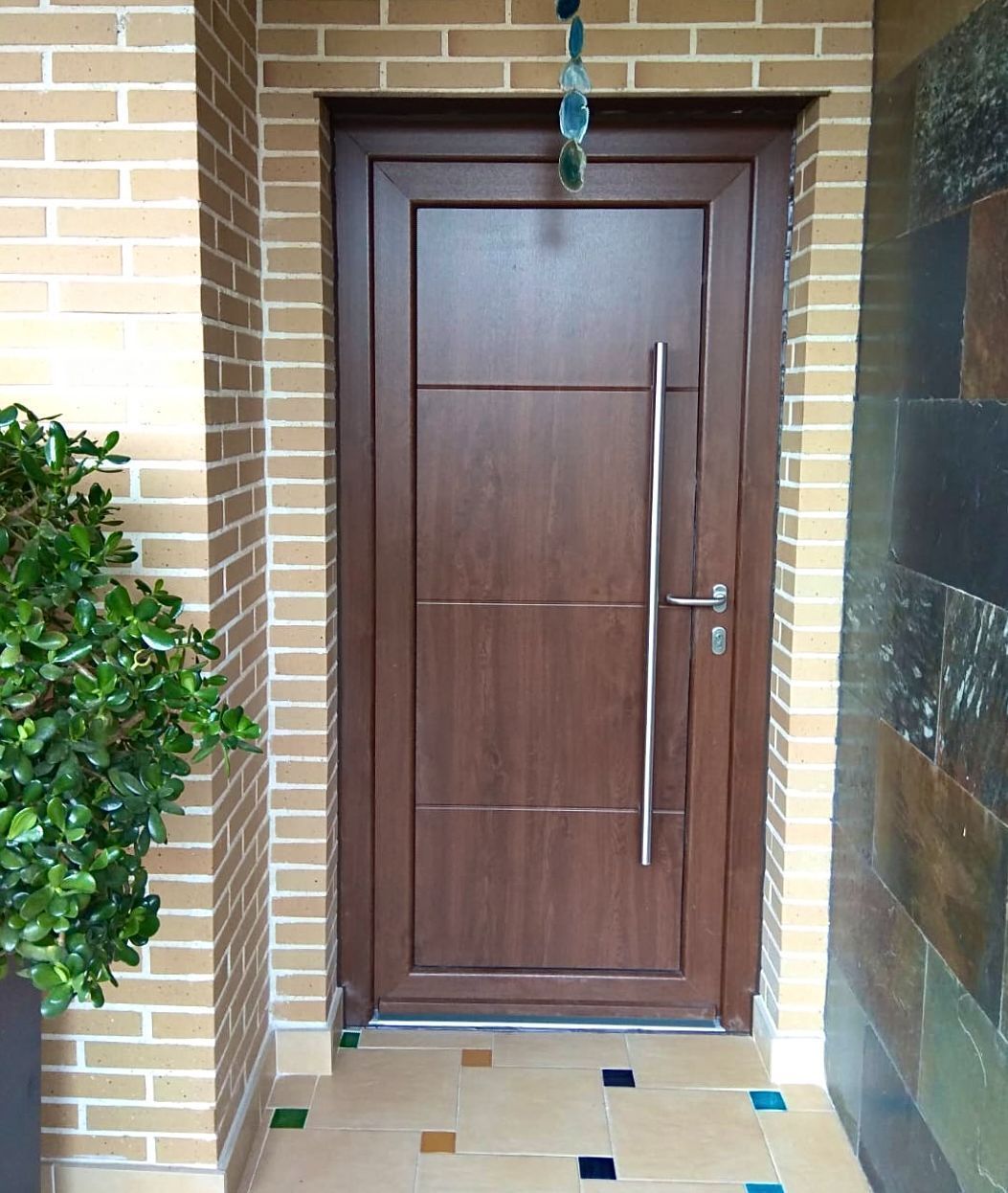 Una puerta de madera con manija de metal está al lado de una pared de ladrillos.