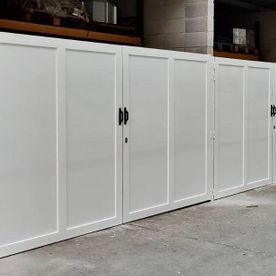 Una fila de puertas de garaje blancas con manijas negras sobre un piso de concreto.