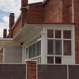 Un edificio de ladrillo con un porche blanco y muchas ventanas.