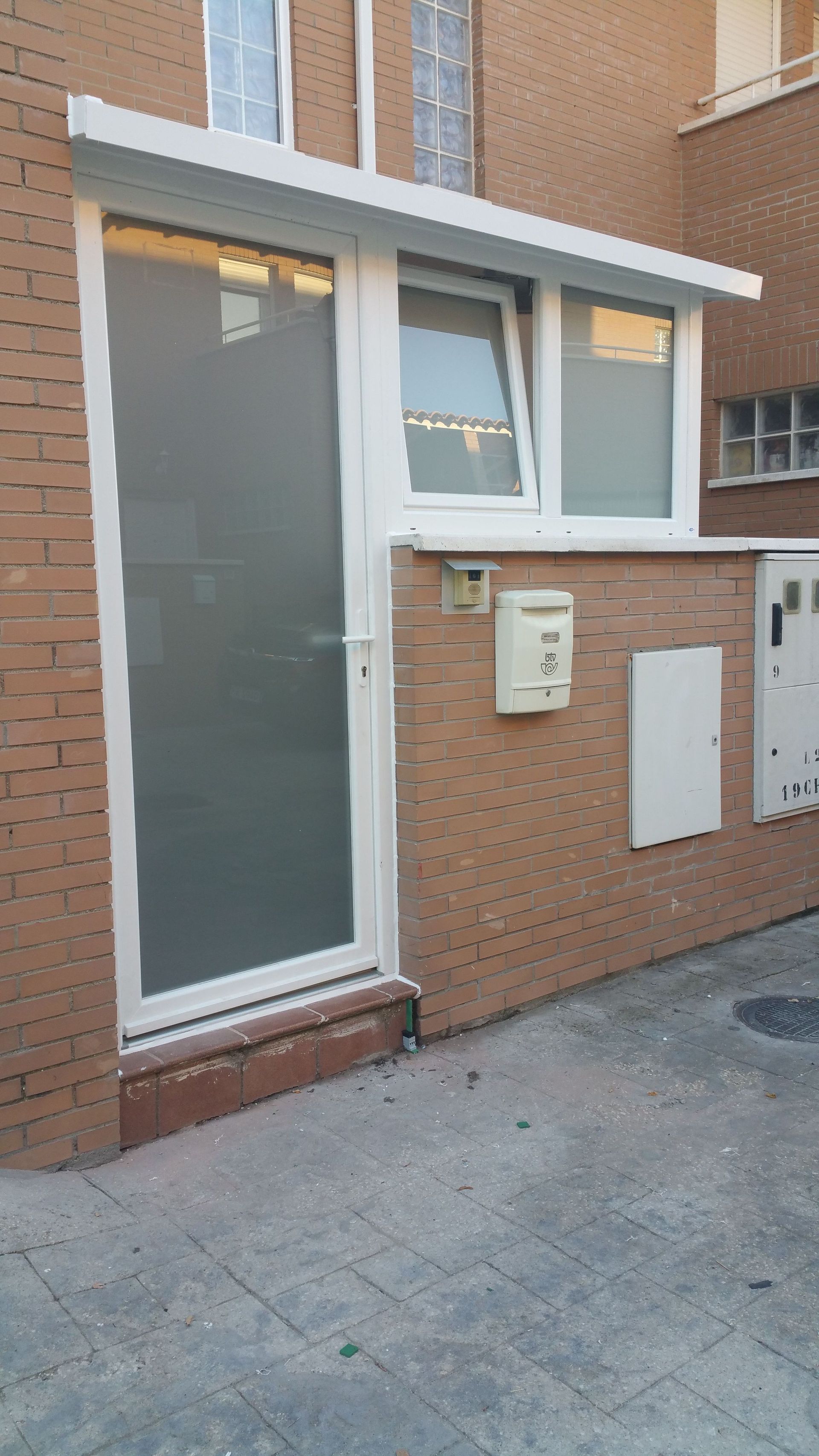 Un edificio de ladrillo con una puerta blanca y un buzón blanco.