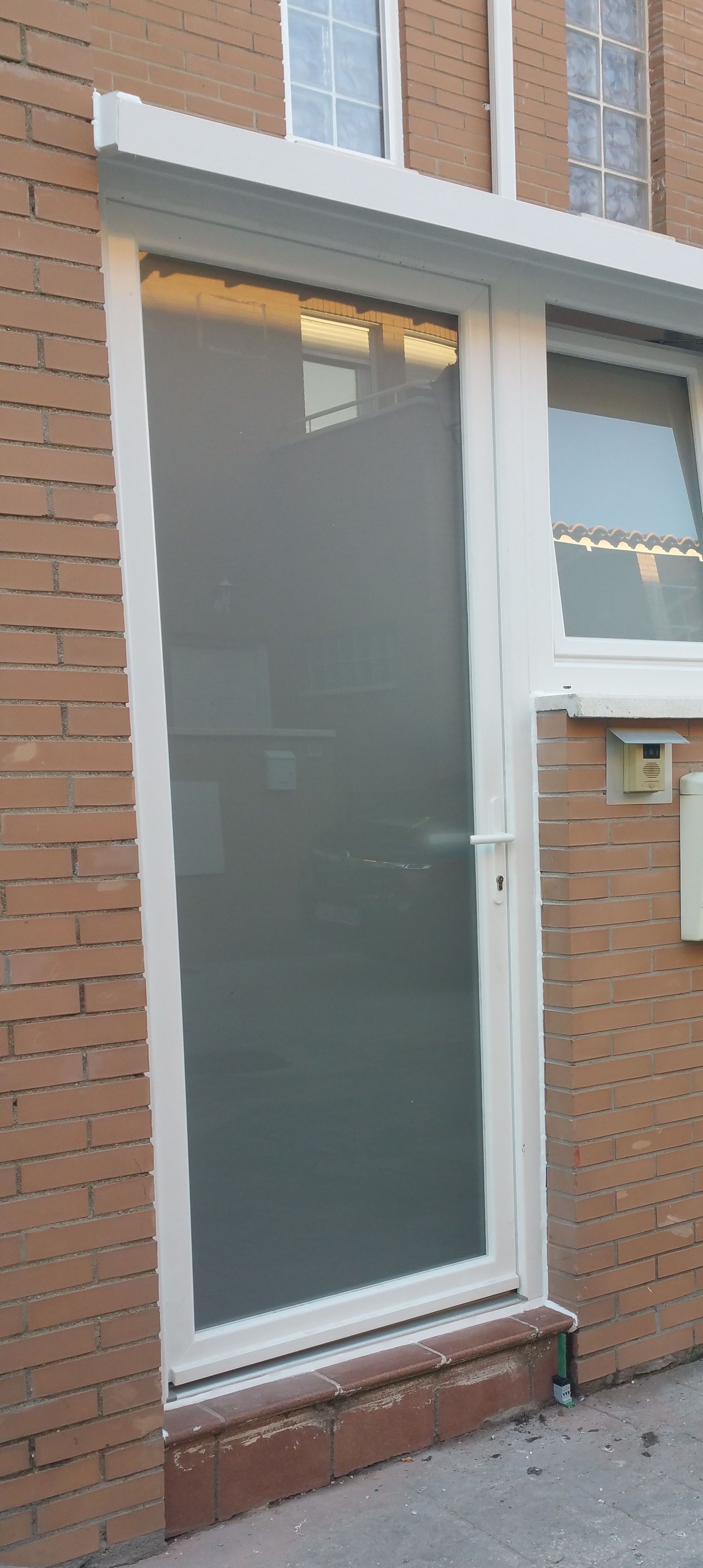 Una puerta blanca está en el costado de un edificio de ladrillo.