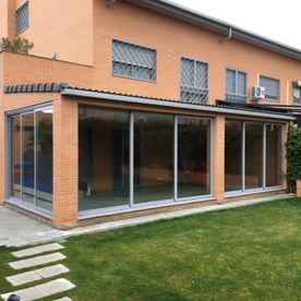 Una casa grande con muchas ventanas y un césped delante de ella.