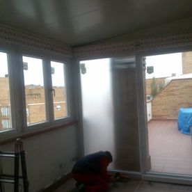 Un hombre está trabajando en una puerta corrediza de vidrio en una habitación.