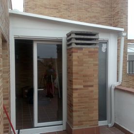 Un edificio de ladrillo con una puerta corrediza de vidrio y una chimenea.