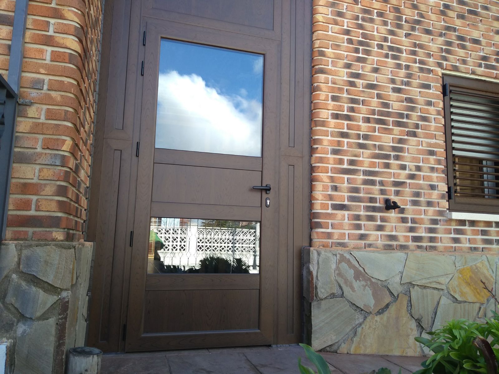 Un edificio de ladrillo con una puerta marrón y una ventana.