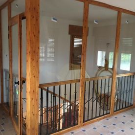 Un pasillo con una escalera y una pared de cristal.