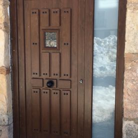 Una puerta de madera con una ventana de vidrio en una pared de piedra.