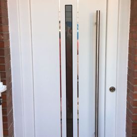 Una puerta blanca con manija de acero inoxidable en una pared de ladrillos.