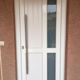 Una puerta blanca con manija de acero inoxidable en una pared marrón.