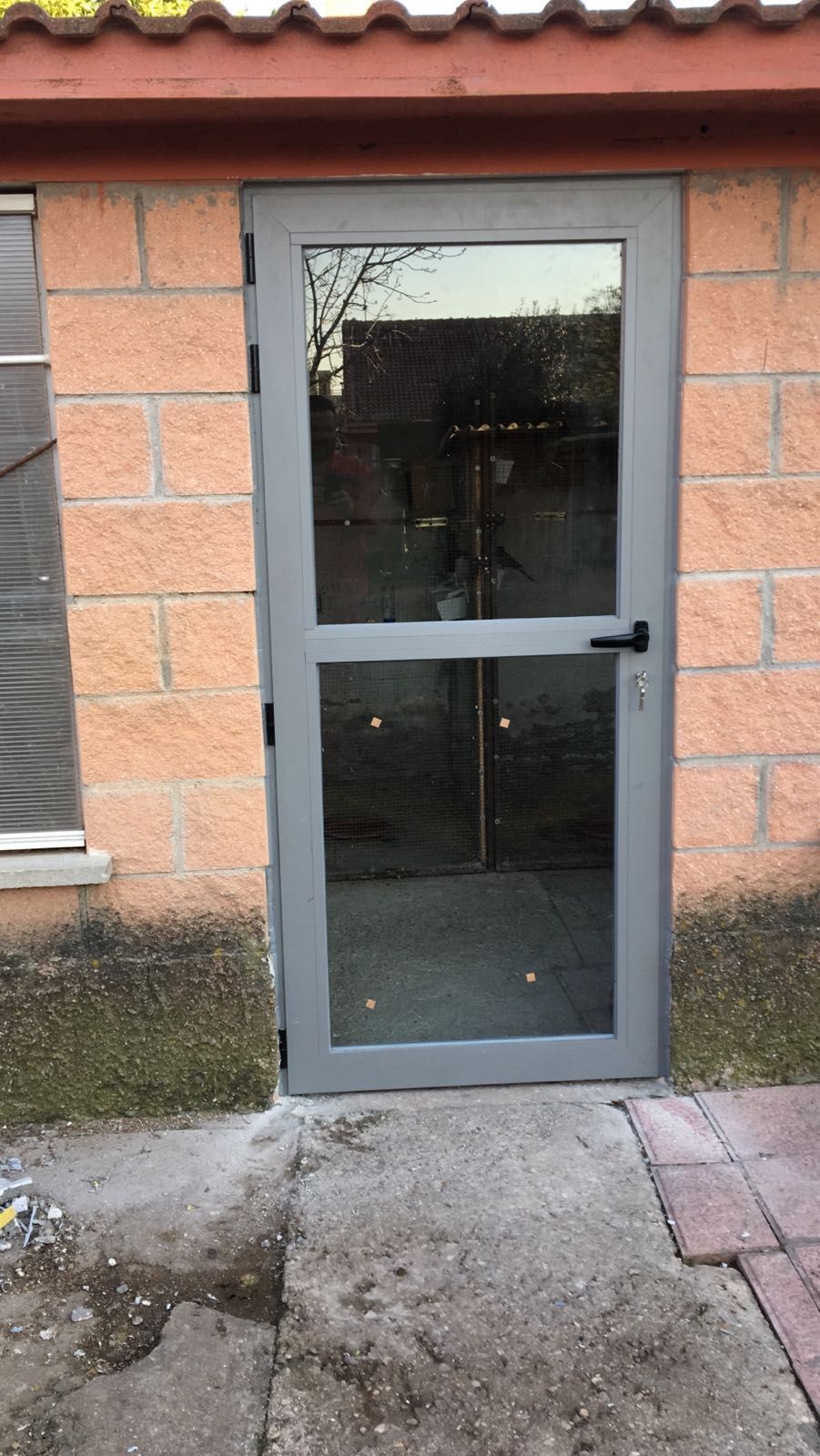 Una puerta con una ventana de vidrio está frente a un edificio de ladrillos.