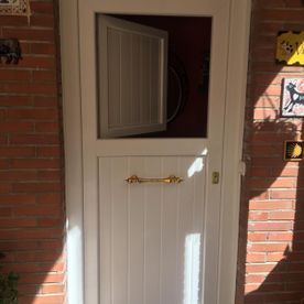 Una puerta blanca con una ventana de vidrio en una pared de ladrillos.