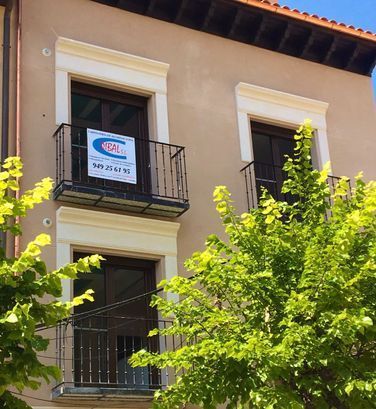 Un edificio con un cartel en el balcón que dice 'alquiler'
