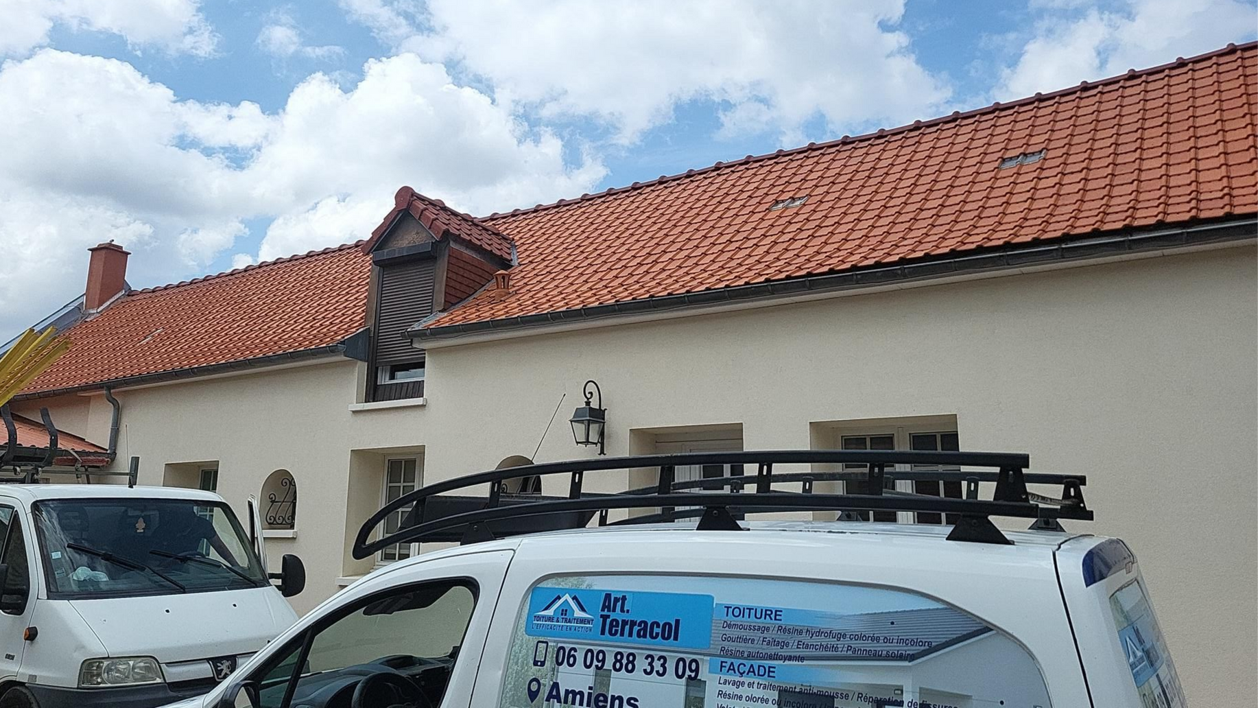 Bâtiment avec la toiture en tuiles et les voitures de l'entreprise devant.