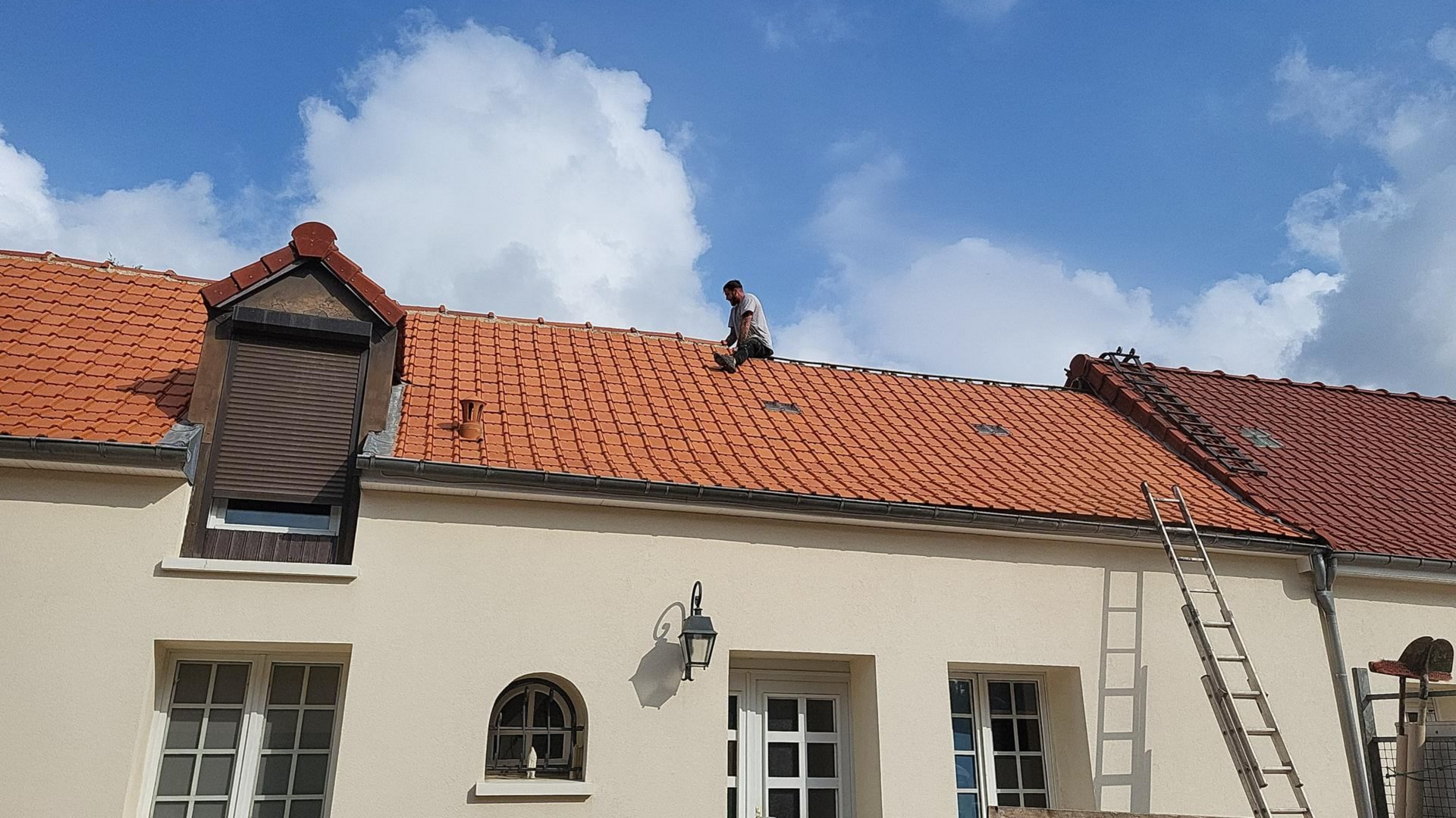 Couvreur assis sur le toit en tuiles.