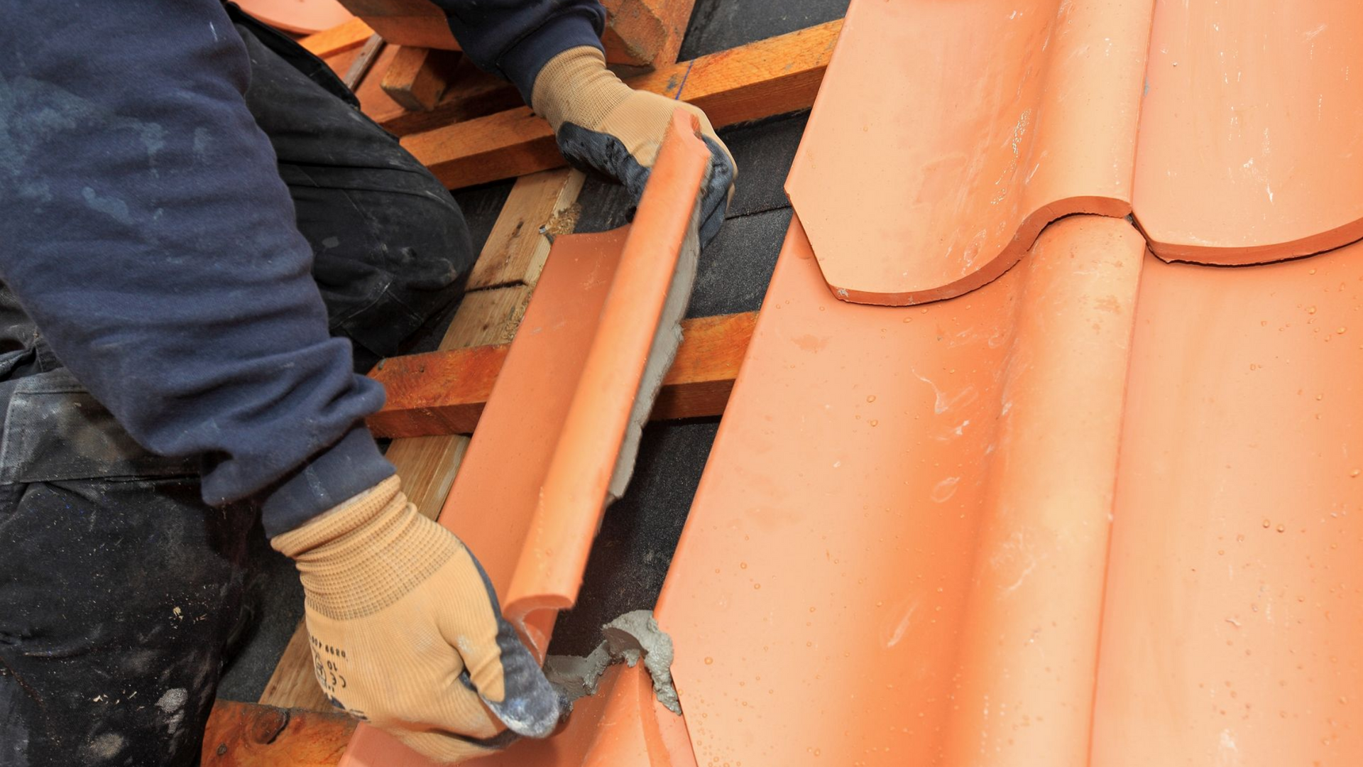 Gros plan sur les mains d'un professionnel en train de poser une tuile.