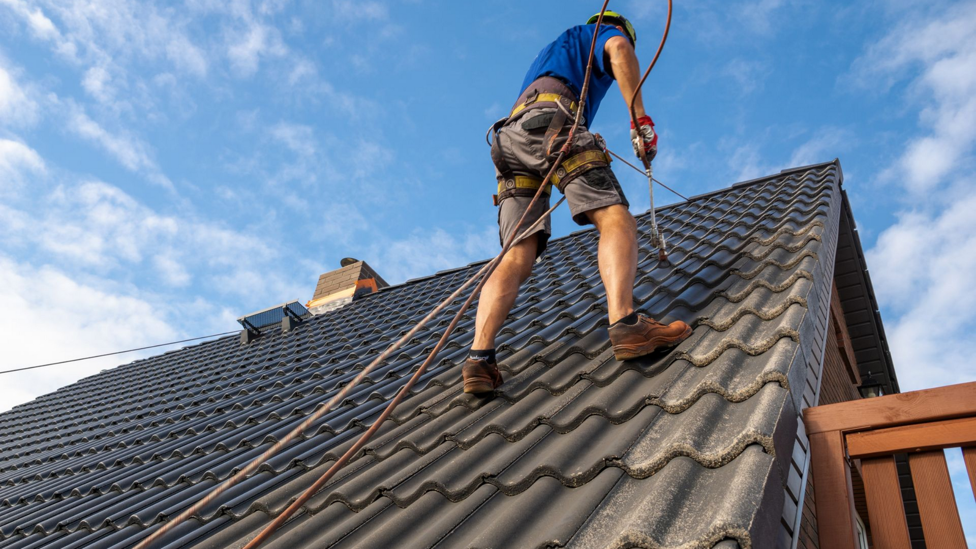 Un couvreur qui est en train d'appliquer un produit sur la toiture d'une maison.