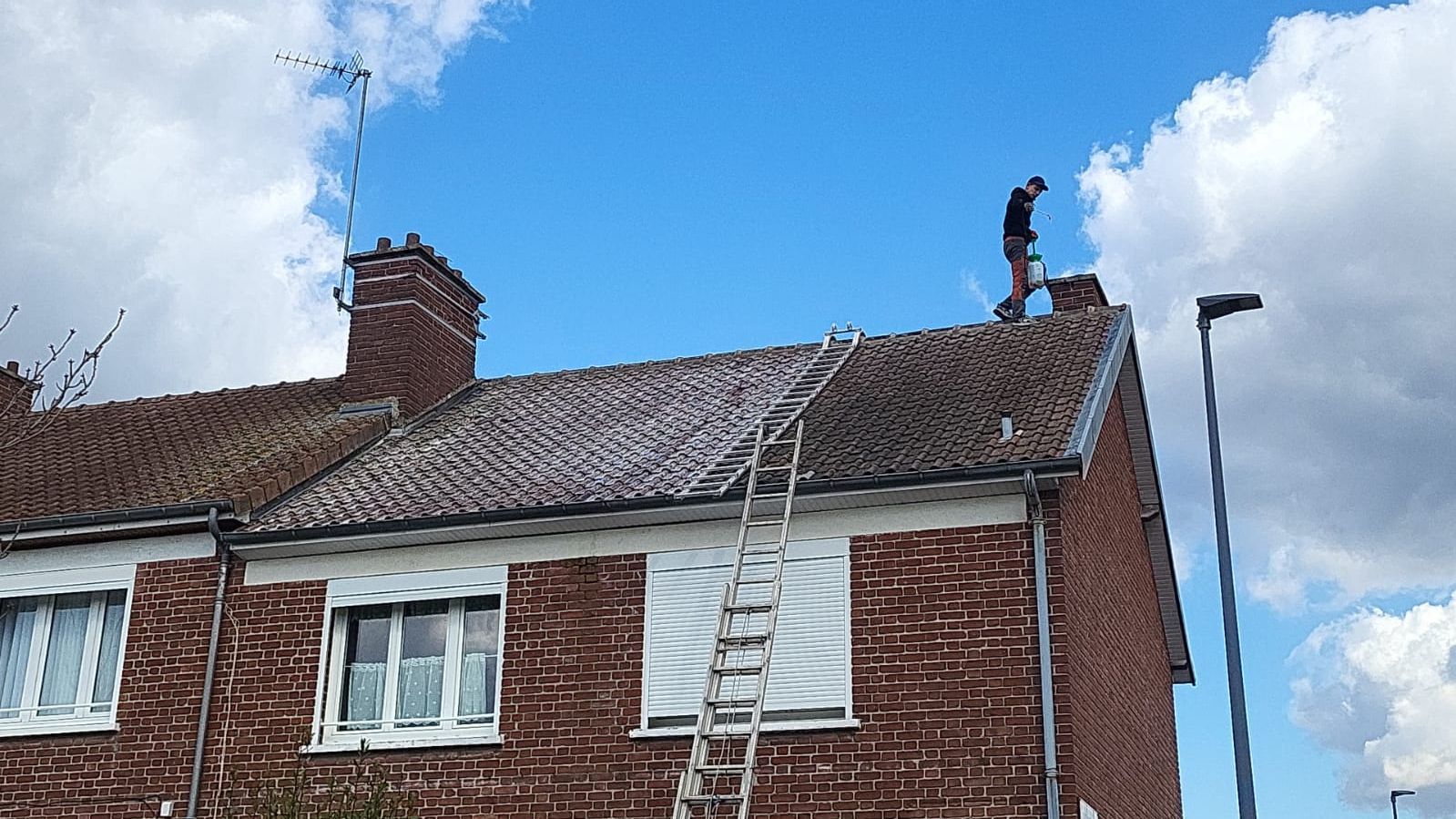 Toiture en tuile couverte de mousses pendant le nettoyage.