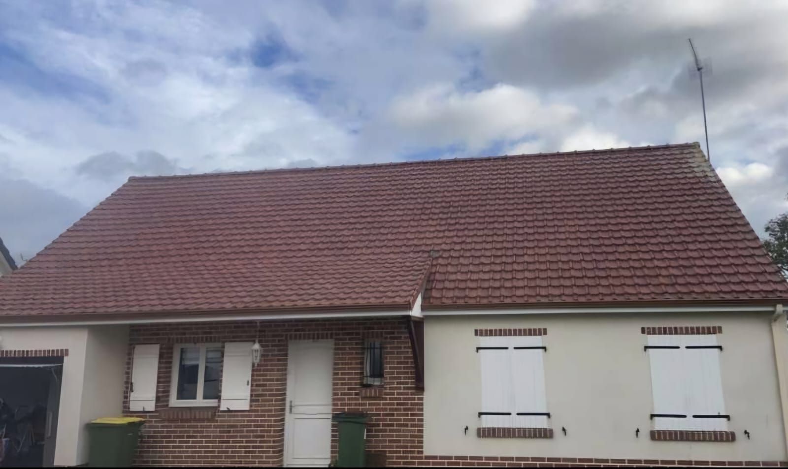 Toiture en tuile d'une maison avec la façade en brique.